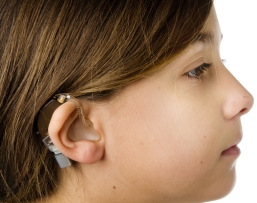 Girl wearing a hearing aid with an FM boot attached to the aid.